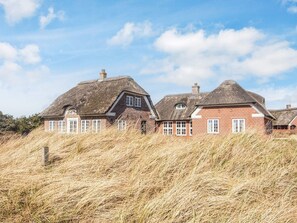 A traditional thatched-roof house with brick walls, set in a grassy landscape. - 5 Star Holiday Home in Blavand (Blavand)
