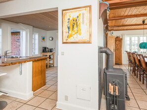 A kitchen with a wooden island, a stove, and a painting on the wall. - 5 Star Holiday Home in Blavand (Blavand)