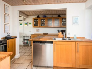 Una cocina moderna con armarios de madera, lavavajillas y pileta.
