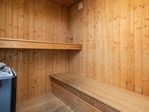 Sauna de fusta amb bancs i un banc a terra.