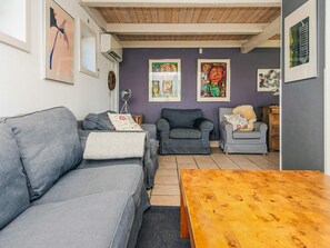 A living room with a grey sofa, a wooden coffee table, and two armchairs.