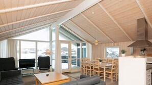 A spacious living area with a sofa, a coffee table, and a television. There is a dining area with a table and chairs, and a kitchen with a stove and cabinets. - Quaint Holiday Home in LÃ¸kken near Beach (Lokken)