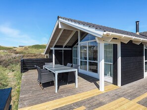 Una casa moderna con terraza, una mesa de comedor y asientos exteriores.