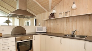 A kitchen with wooden walls, a stainless steel oven, a microwave, a sink, and hanging pendant lights. - Quaint Holiday Home in LÃ¸kken near Beach (Lokken)
