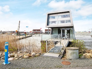A modern building with a flat roof, large windows, and a ramp leading to the entrance.
