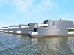 A modern floating building with a flat roof, large windows, and a water barrier. - 4 Star Holiday Home in Hemmet (Hemmet)