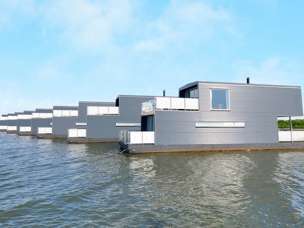 A modern floating building with a flat roof, large windows, and a water level that reaches the base.