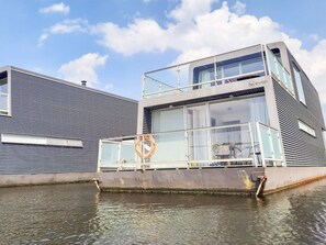 Ein modernes Gebäude mit Glasfassade, einer Rettungsboje und einem Wasserspiegel im Vordergrund.