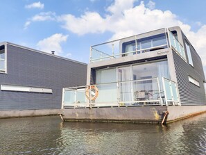 A modern building with a glass facade, a lifebuoy, and a metal railing by the water. - 4 Star Holiday Home in Hemmet (Hemmet)