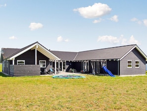A two-story house with a covered patio, a swing set, and a blue slide.
