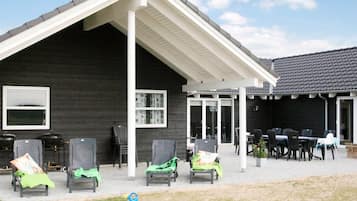 A building with a covered patio area, outdoor seating, and a table.