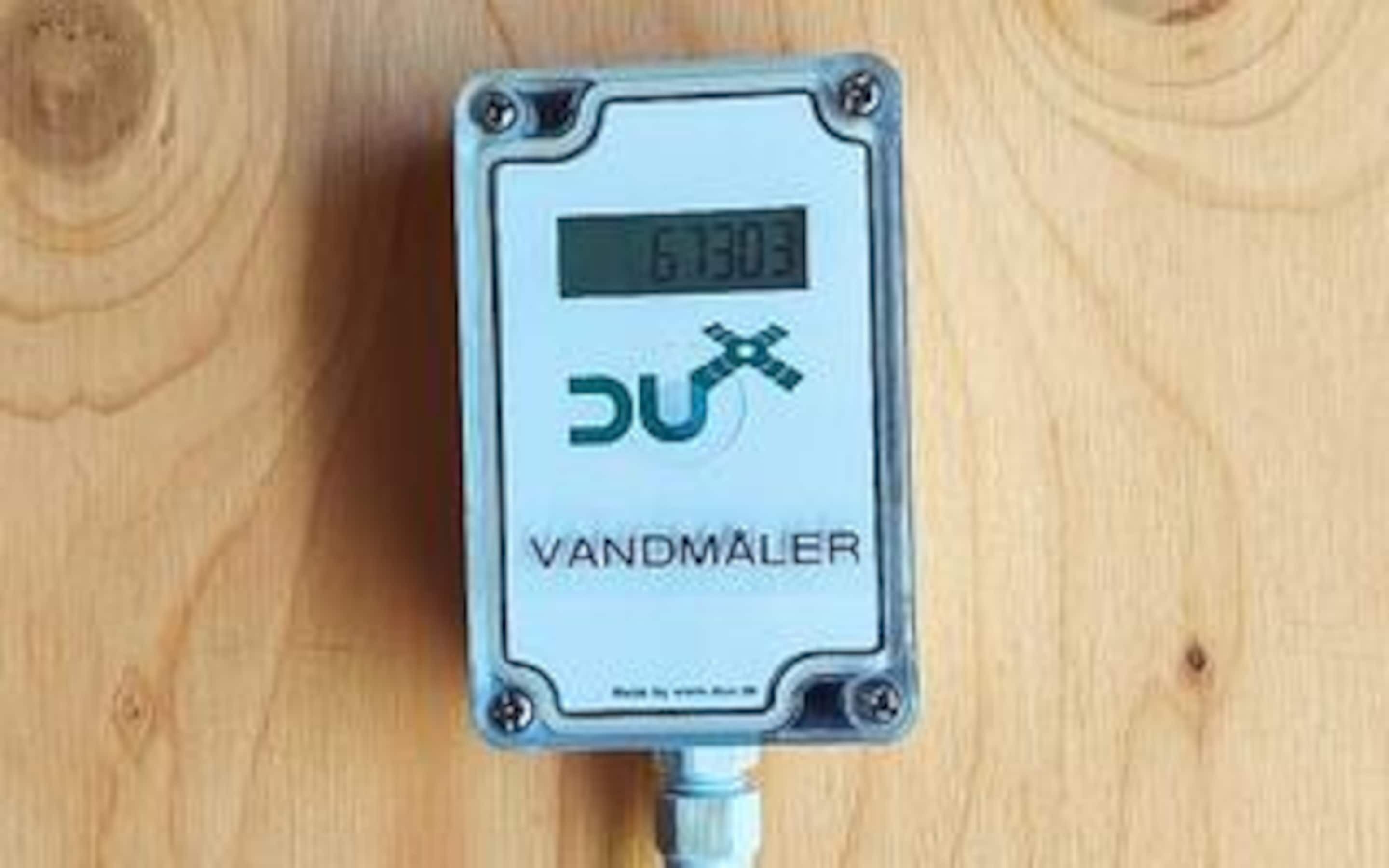 A device with a digital display and the brand name 'VANDMÅLER' on a wooden surface.
