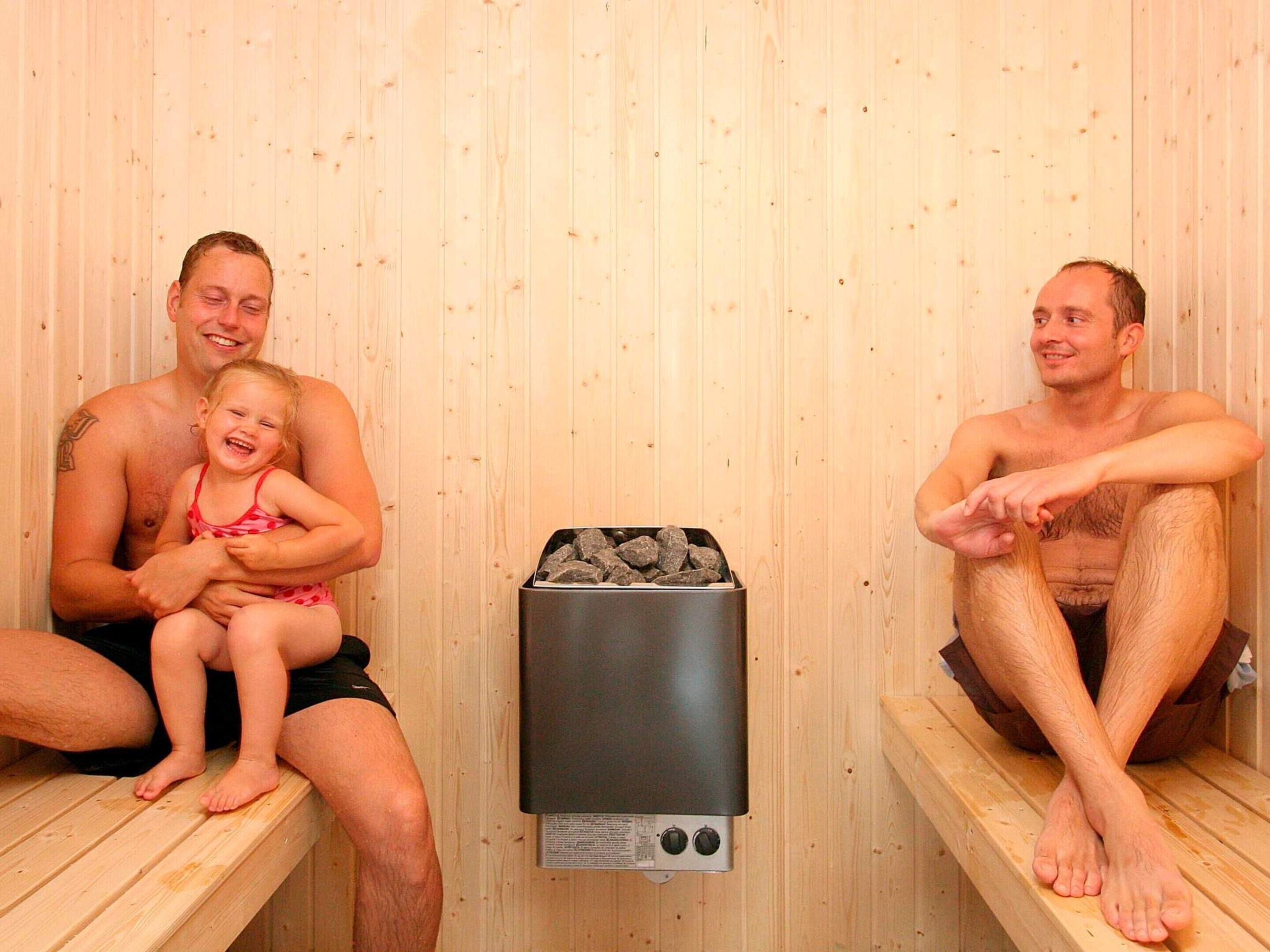 A sauna with wooden benches and a heater in the center.