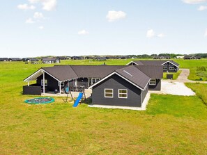 Un barrio residencial con varias casas, un parque infantil y un campo verde.