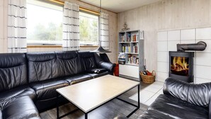 Un salon chaleureux avec un canapé en cuir noir, une table basse en bois, une bibliothèque et une cheminée.