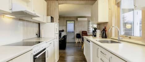 A modern kitchen with white cabinetry, a built-in oven, and a coffee maker.