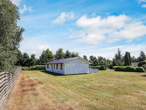 Un bâtiment blanc d’un seul étage, surmonté d’un toit sombre, entouré d’une pelouse bien entretenue et d’une clôture en bois.