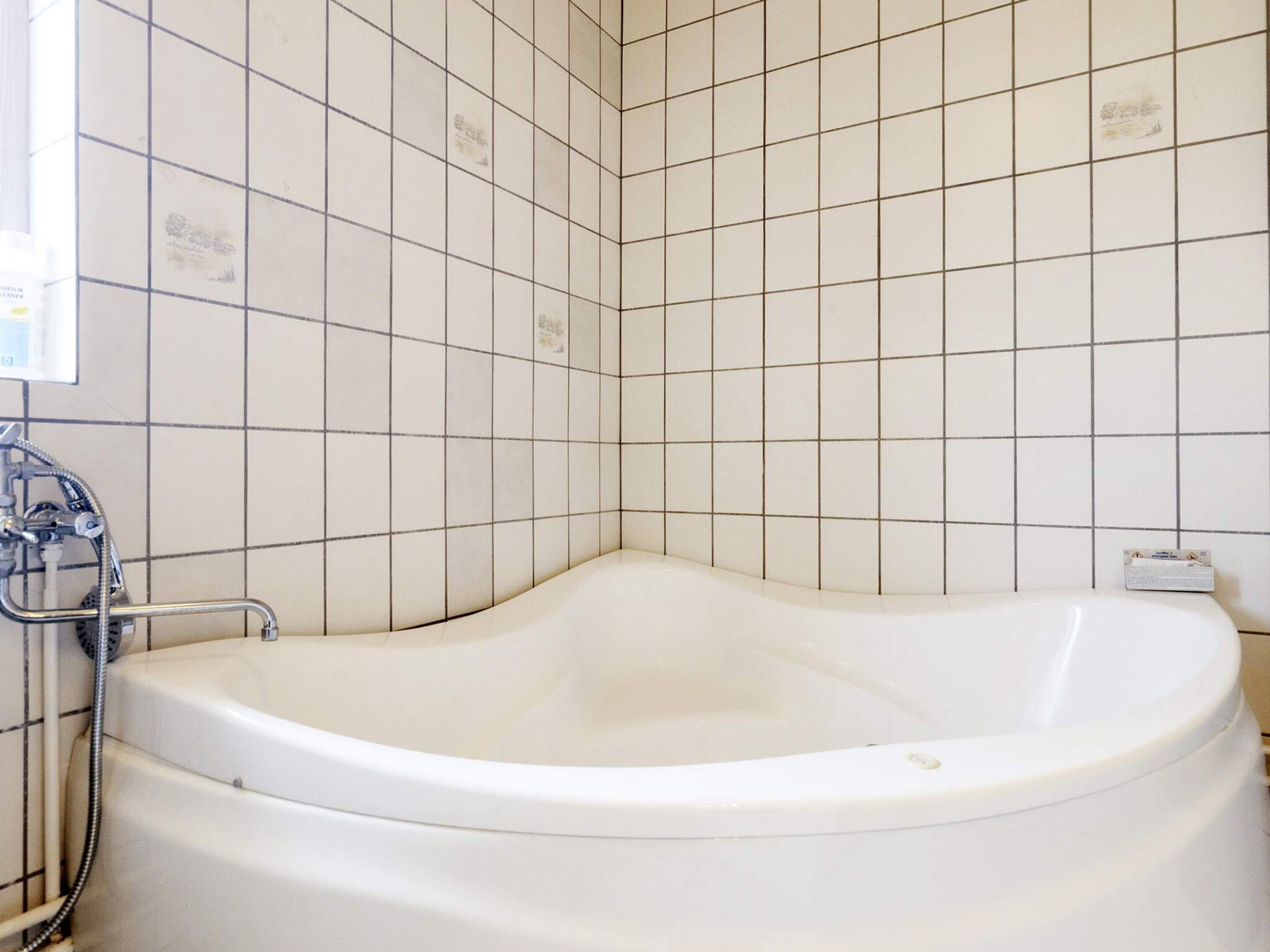 A bathroom with a freestanding bathtub, a showerhead, and a toilet.