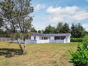 A single-story house with a sloped roof, surrounded by a fenced yard and trees. - Enticing Holiday Home in Falster near Sea (Vaeggerlose)