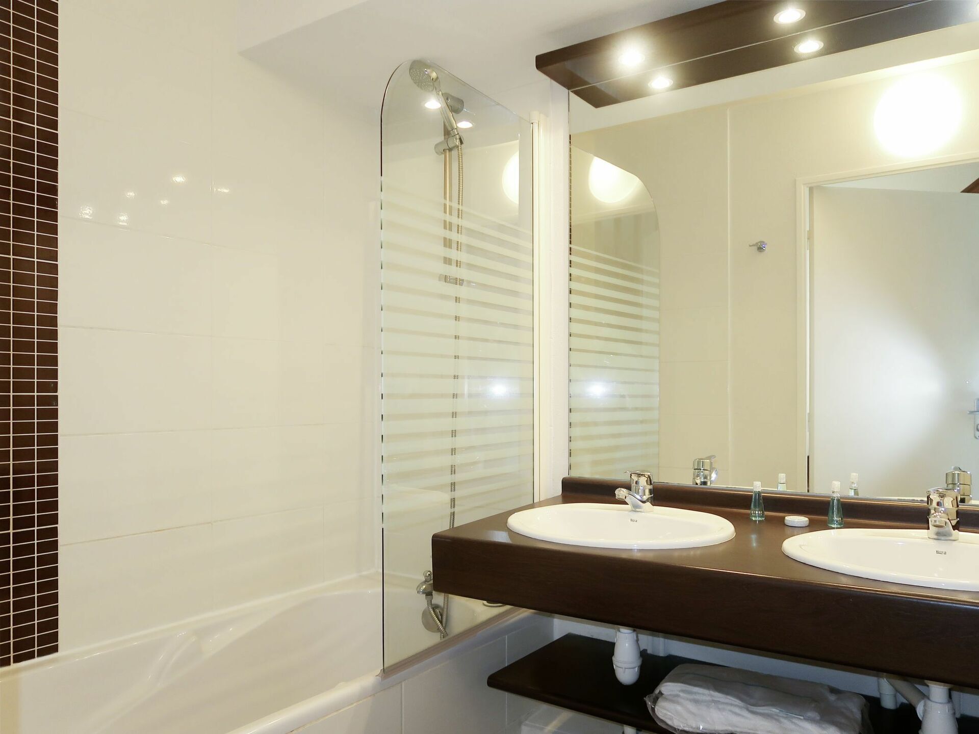 A bathroom with two sinks, a shower, and a large mirror.