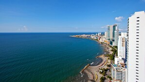 Paisagem costeira urbana com edifícios altos, uma praia e céu azul claro.