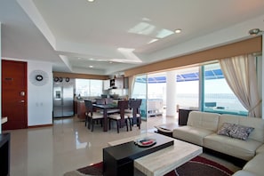 A modern living room with a sofa, a coffee table, and a dining area with chairs and a table.