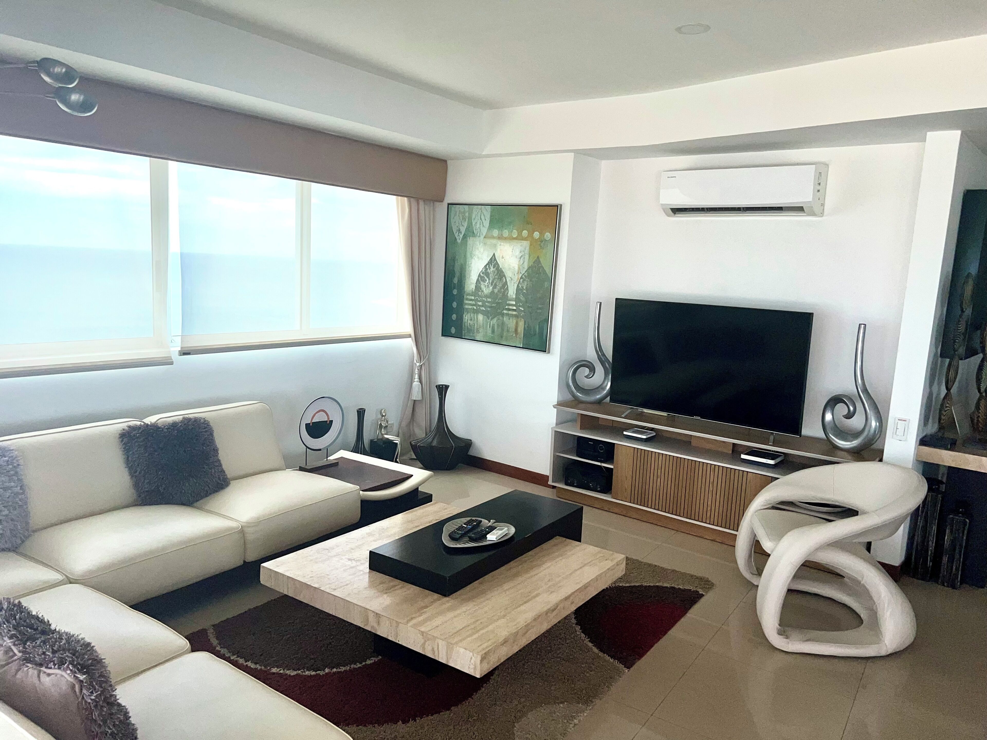 A modern living room with a sofa, coffee table, TV, and decorative vases.