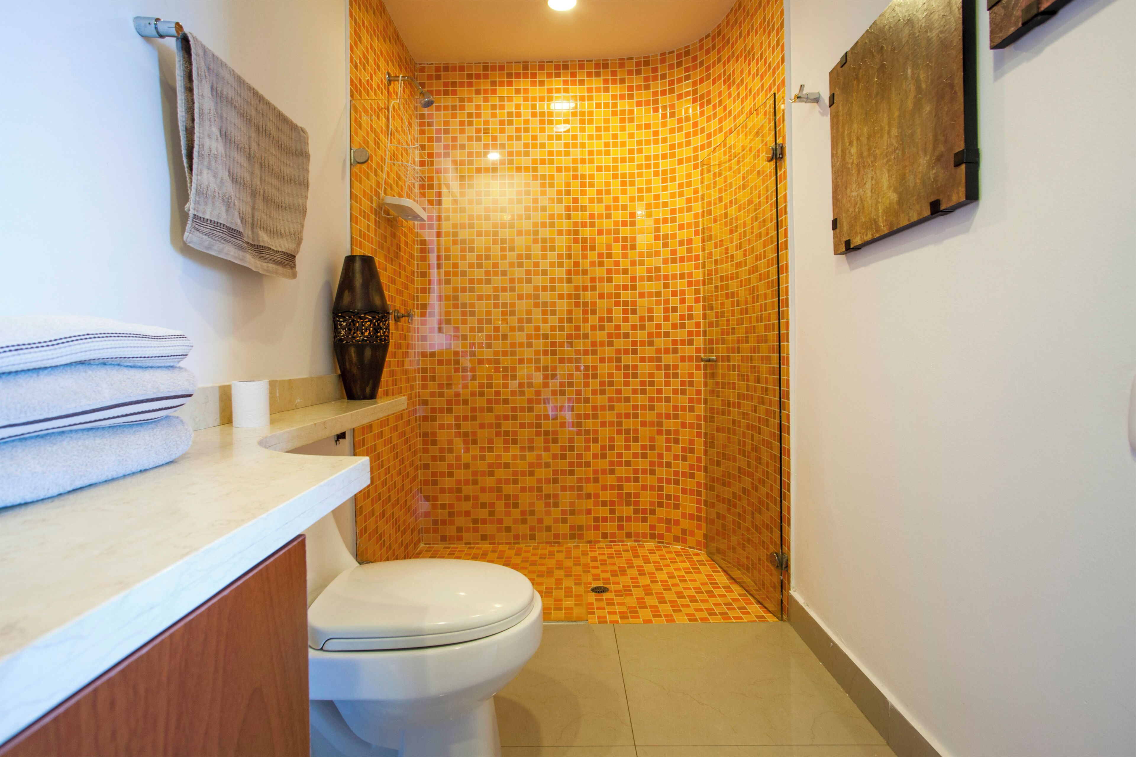 A bathroom with a shower, toilet, and a sink with towels.