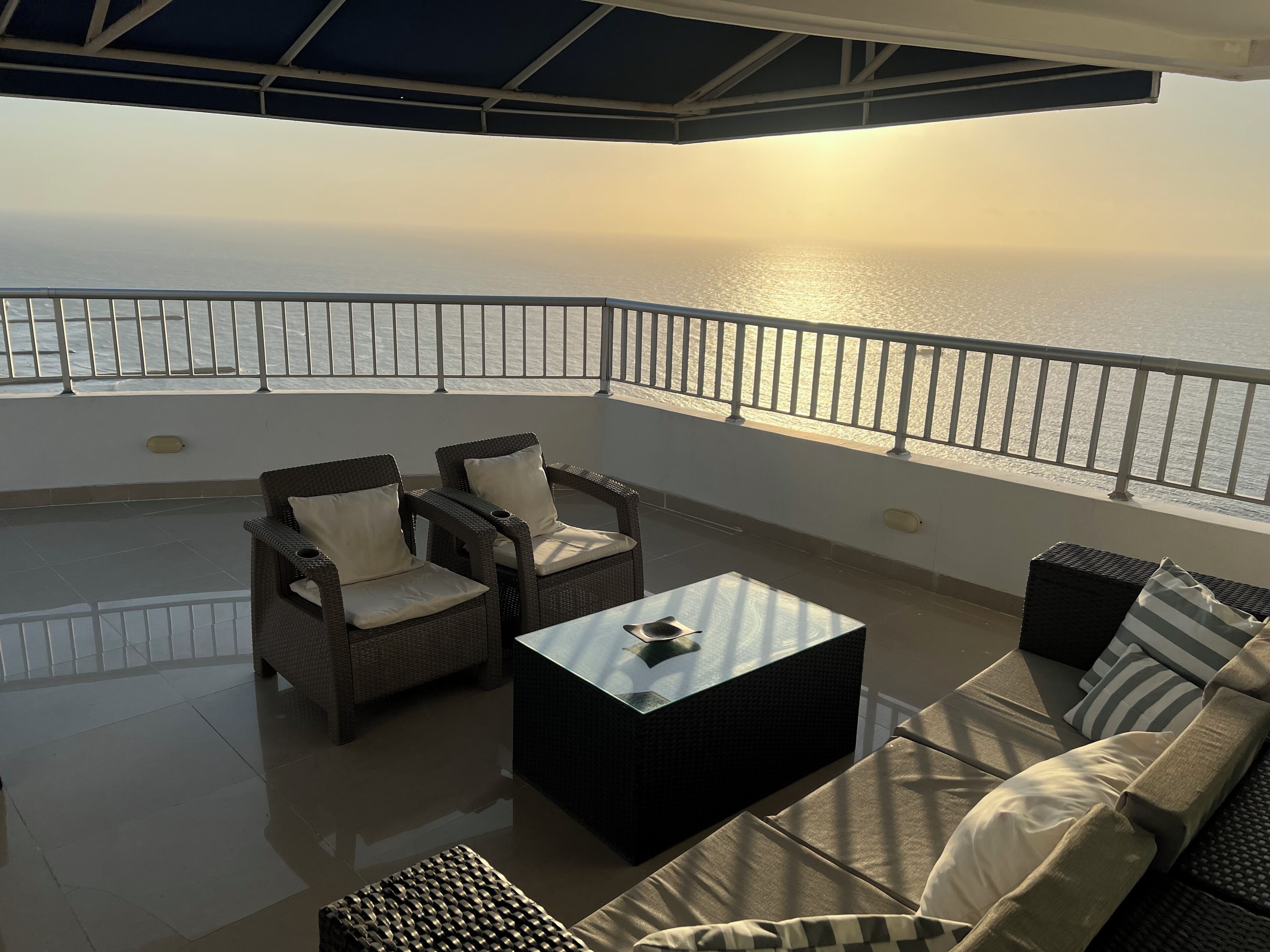 Un balcone con mobili in vimini e un tavolo in vetro, con vista sul mare.