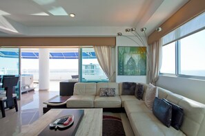 A modern living room with a sofa, coffee table, and a view of the balcony. - Palmetto Penthouse Deluxe Beautiful View and Sunset Floor 39 (Cartagena)