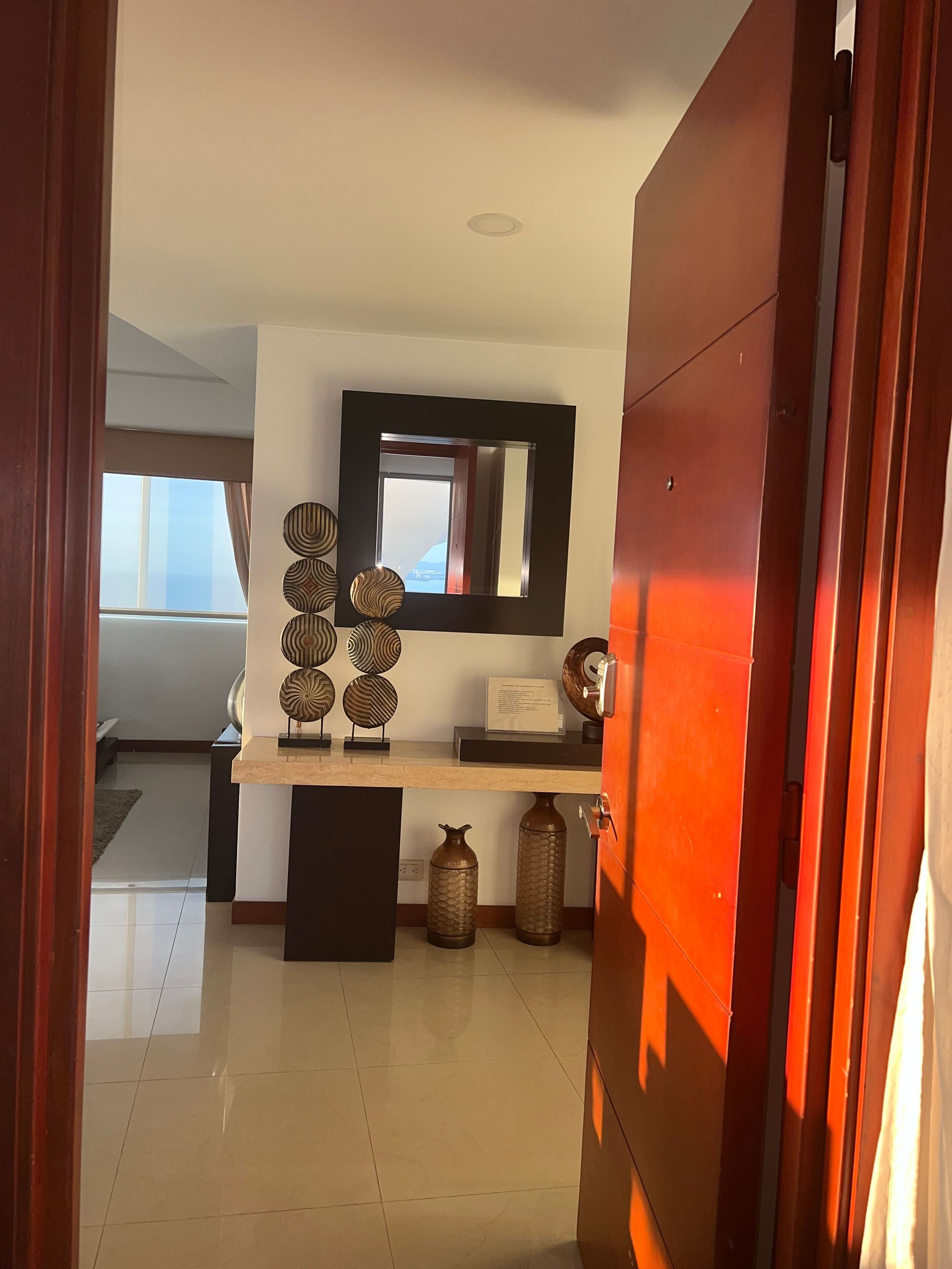 A modern interior with a wooden door, a mirror, decorative plates, and a tiled floor.