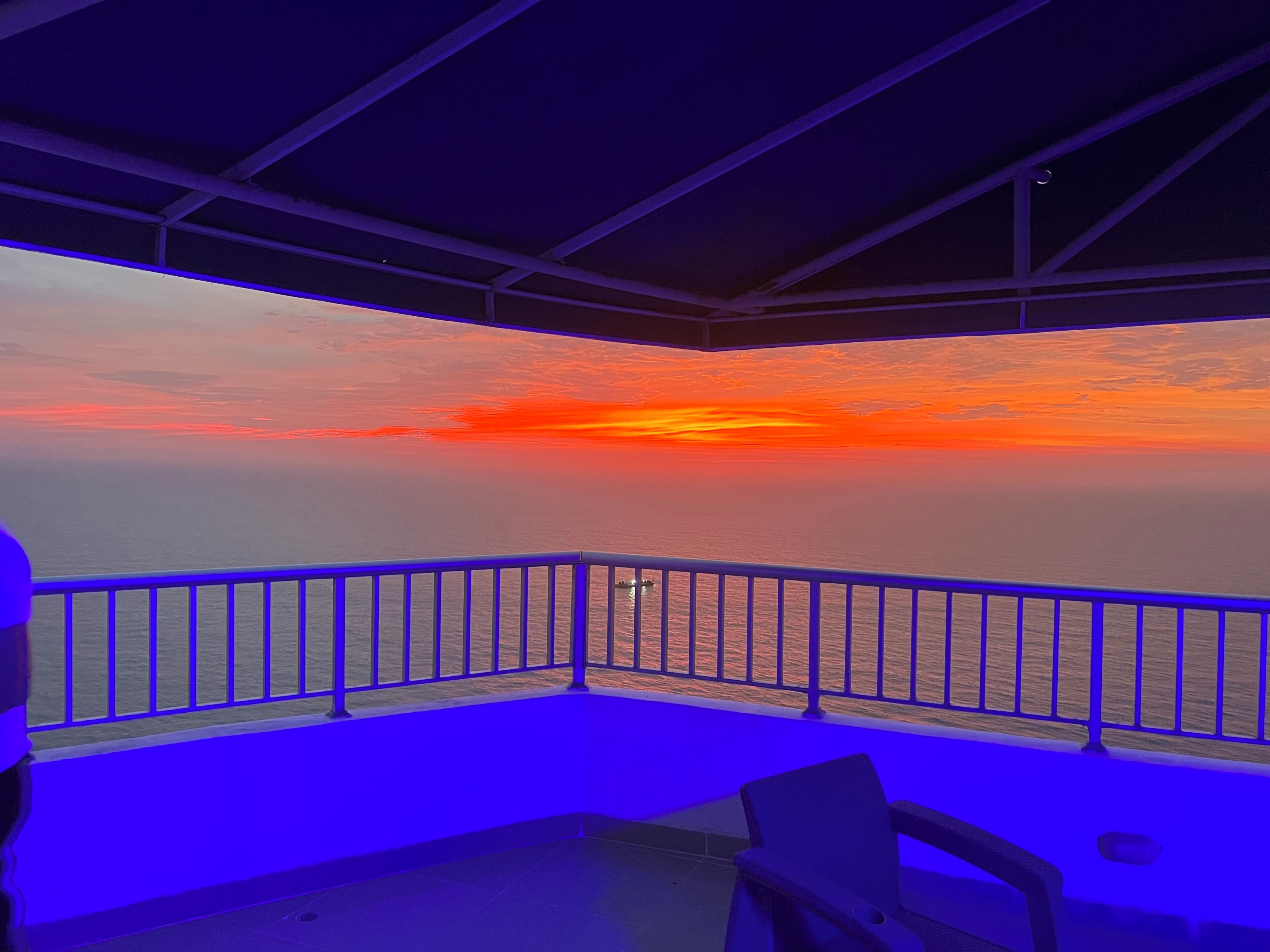 A balcony with a view of the ocean during sunset.