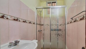 Een badkamer met douche, toilet en wastafel.