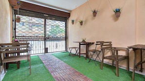 Een balkon met een vloer van groen kunstgras, houten meubilair en hangende plantenpotten.