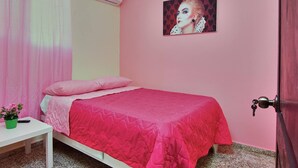 Een slaapkamer met een bed, een nachtkastje met een afstandsbediening en een schilderij aan de muur.