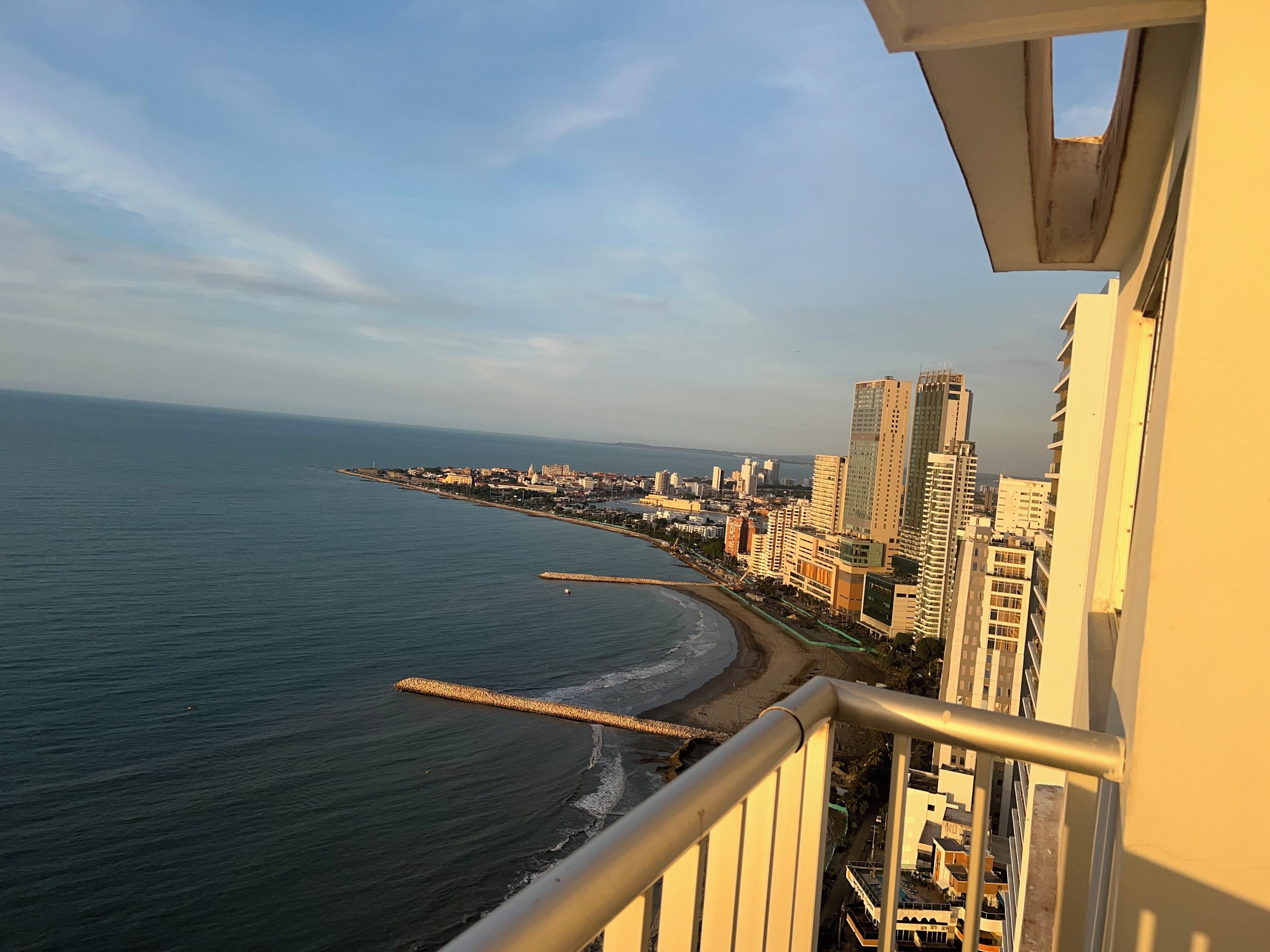 Un paysage urbain côtier avec de hauts immeubles, une plage et un ciel dégagé.
