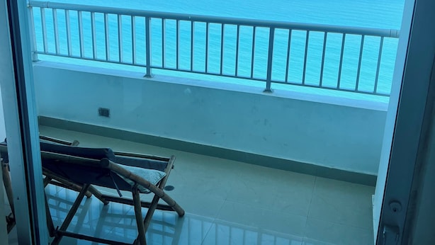 Ein Balkon mit Blick auf das Meer, einem Metallgeländer und einem Klappstuhl.