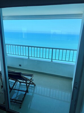 Ein Balkon mit Blick auf das Meer, einem Metallgeländer und einem Klappstuhl.