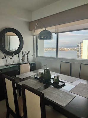 A modern dining area with a view of a cityscape through large windows. - Palmetto Suite Superior 3901 (Cartagena)
