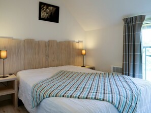 A bedroom with a large bed, two bedside lamps, a headboard, a framed picture on the wall, and a window with curtains. - Beautiful apartment for 4 people with WIFI, pool, TV, terrace and pets allowed (La Houle)
