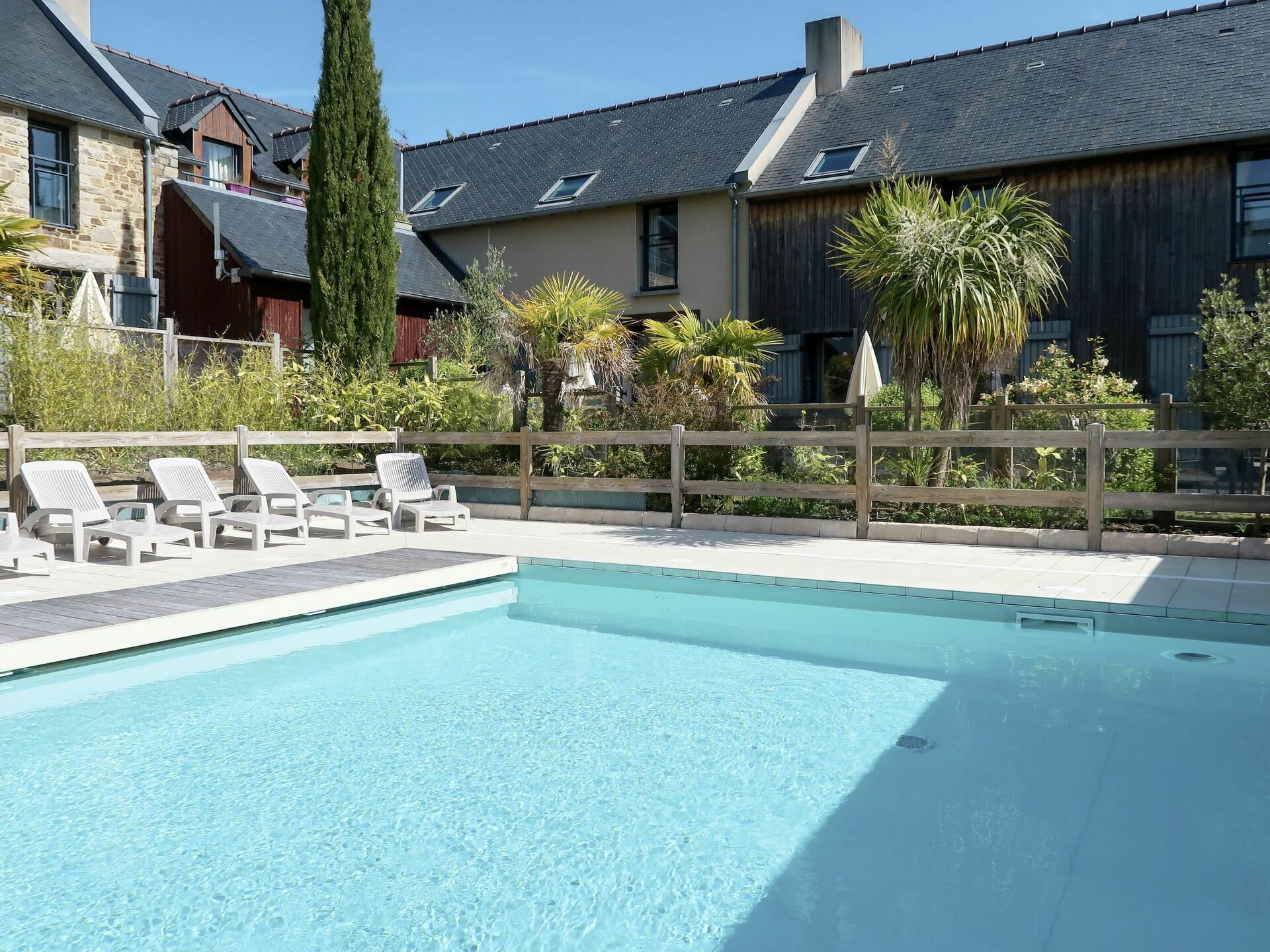 Une piscine avec des chaises longues et une clôture en bois.