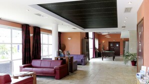 Un vestíbulo espacioso con mesa de billar, un sofá rojo y mesa de futbolín.