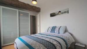 A bedroom with a bed, a nightstand, a wall-mounted artwork, and a sliding door. - Charming Breton house with all comforts (ST ADRIEN)