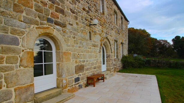 A stone building with a paved patio and a wooden bench. - Charming Breton house with all comforts (ST ADRIEN)