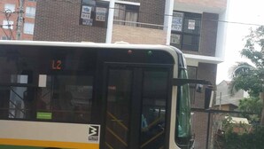 Um ônibus estacionado em uma rua da cidade, com um edifício alto ao fundo.