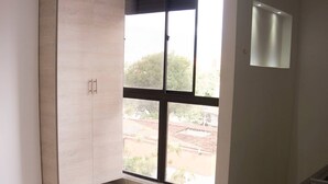 Quarto com uma janela grande, um guarda-roupa e piso ladrilhado.