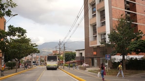 Una calle con un autobús, edificios y personas caminando.