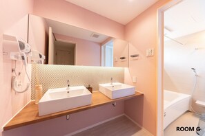 A modern bathroom with two sinks, a large mirror, and a shower.