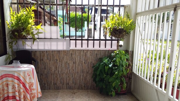 A small, enclosed patio area with a tiled floor, a table with a floral tablecloth, and potted plants. - Room-green Sea Inn Villa Helen Kilometer (San Andrés)