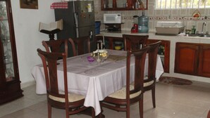 A dining area with a round table, wooden chairs, and a white tablecloth. - Room-green Sea Inn Villa Helen Kilometer (San Andrés)